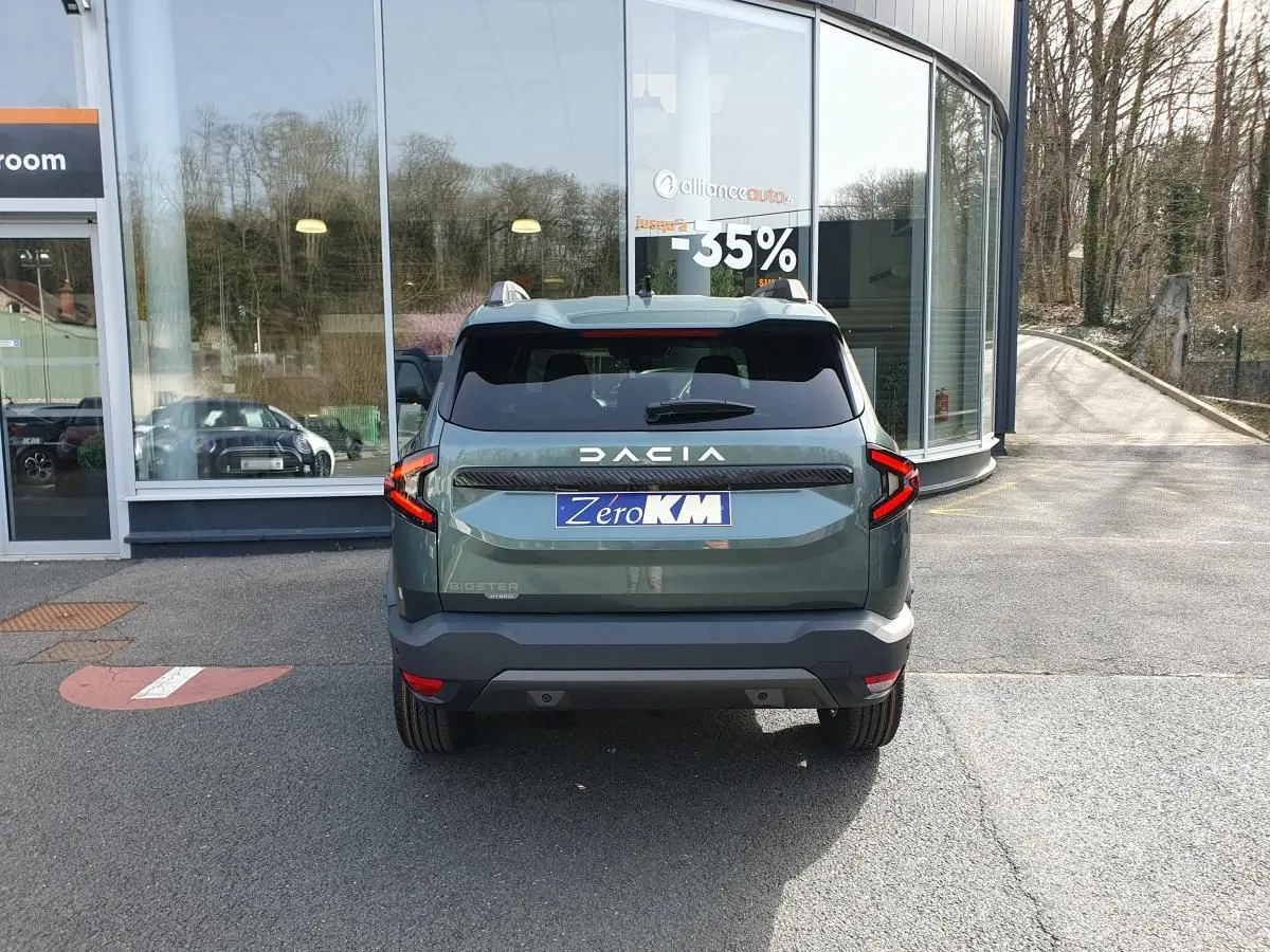 Vue arrière du Dacia Bigster vert cèdre avec toit panoramique et feux LED distinctifs, stationné devant une vitrine.