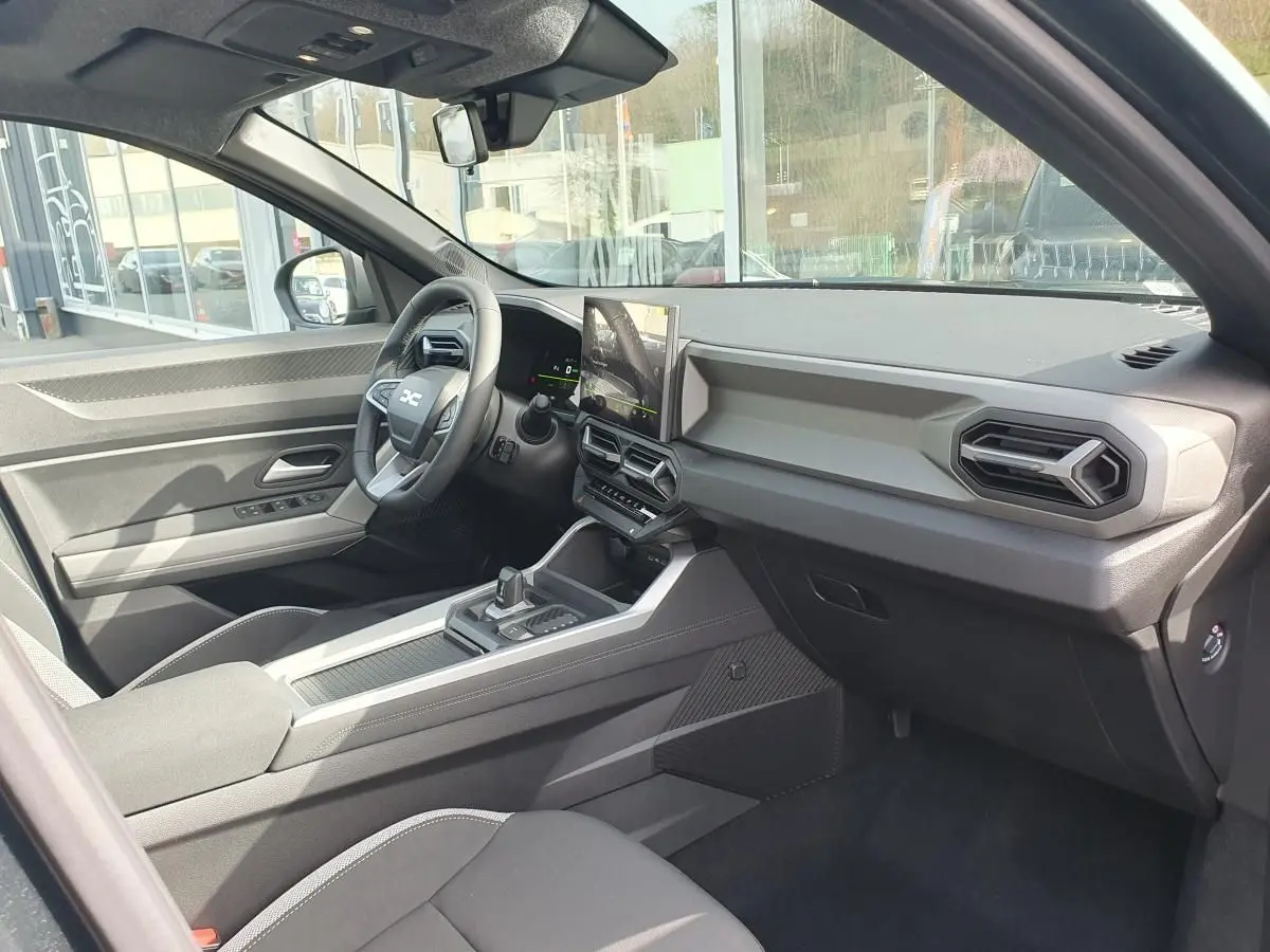 Intérieur du Dacia Bigster 2026 vu côté conducteur, tableau de bord moderne avec écran tactile vertical et volant multifonction.