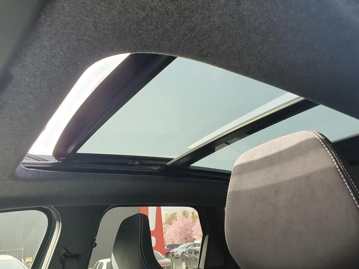 Vue intérieure du toit panoramique ouvert du Dacia Bigster 2026, avec ciel visible et appui-tête avant gris foncé.