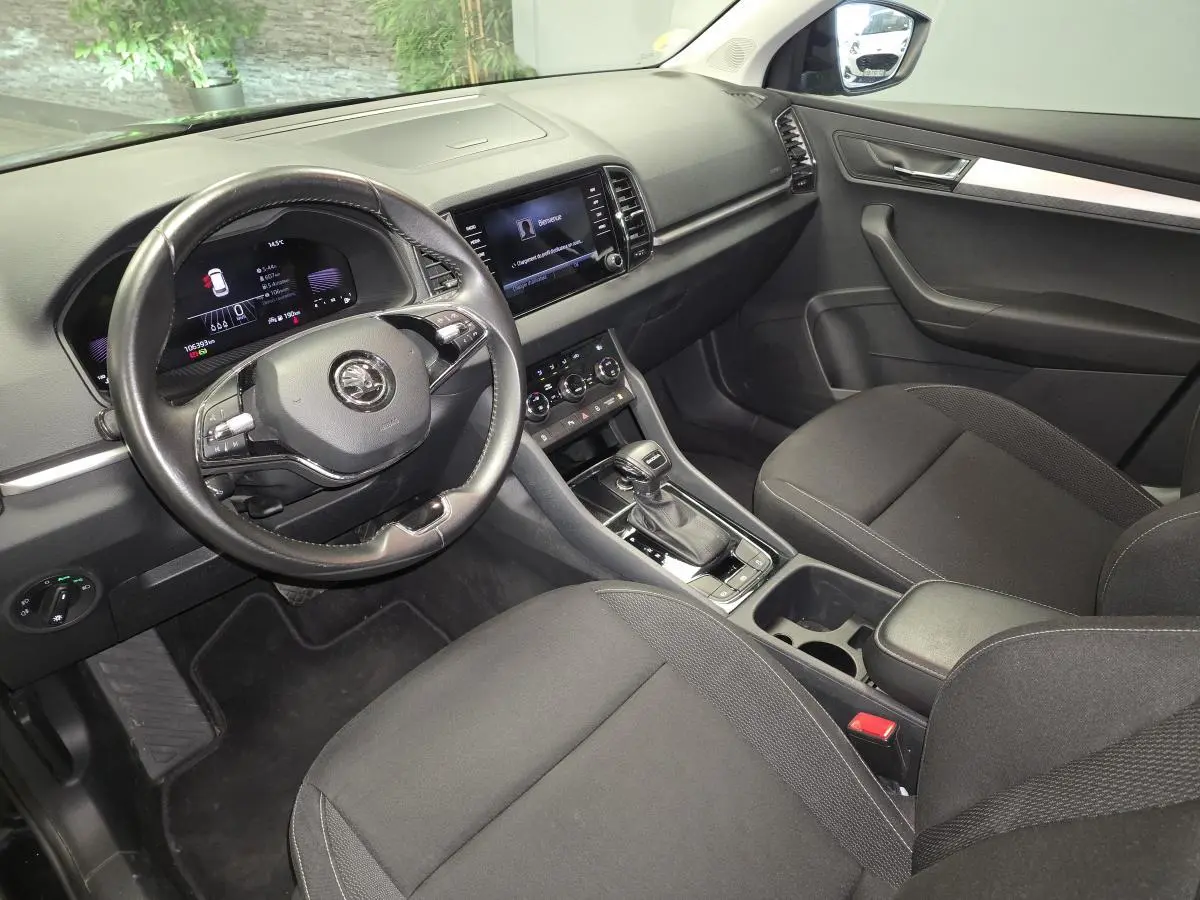 Vue intérieure avant droite du Skoda Karoq 2023 noir, avec volant cuir, tableau de bord digital et console centrale moderne.