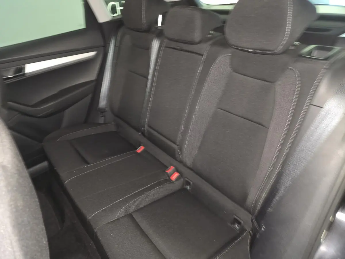 Vue intérieure du siège arrière côté droit en tissu noir du Skoda Karoq 2023 avec appuie-têtes et ceintures visibles.