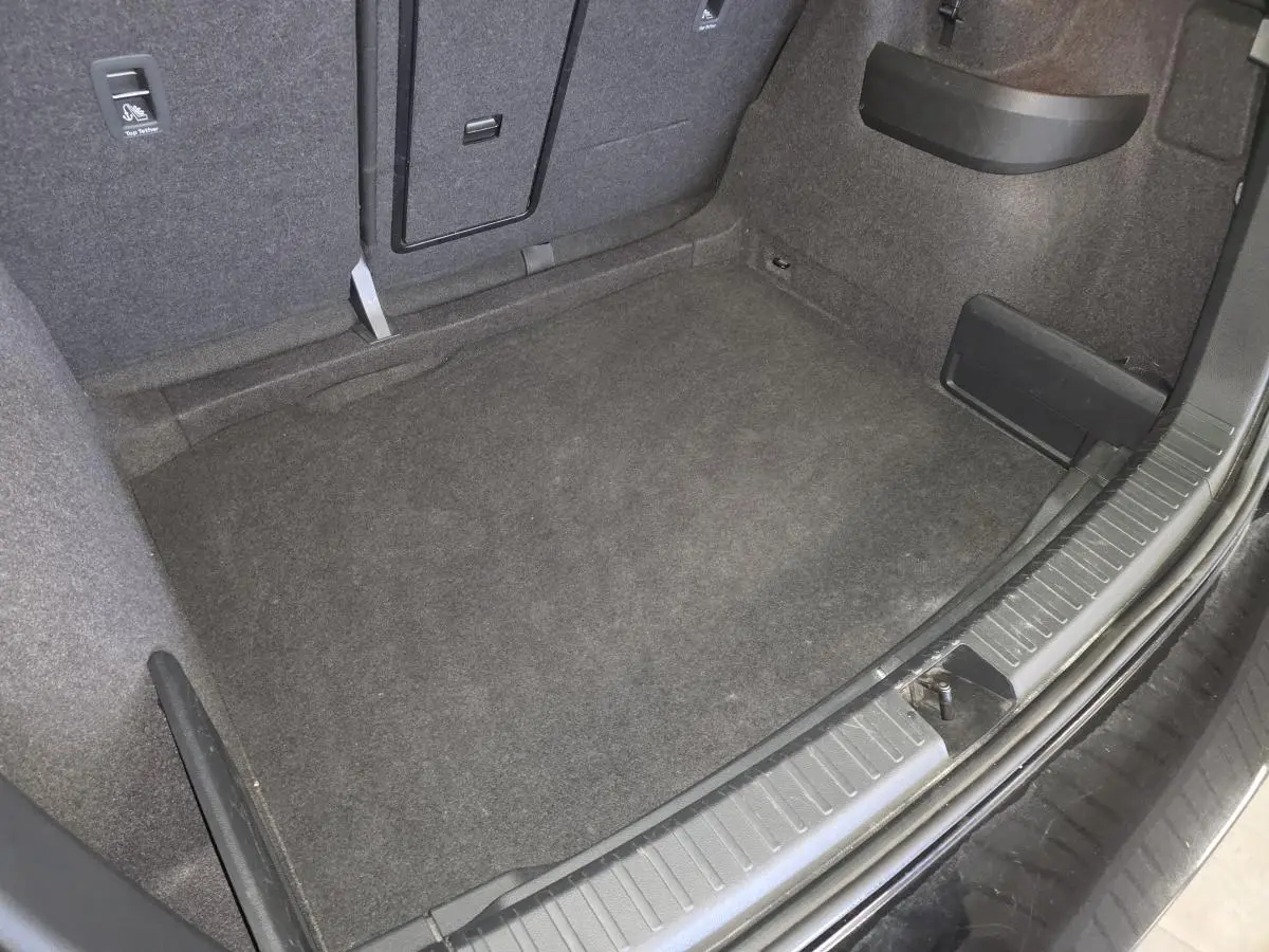 Coffre spacieux vu de dessus du Skoda Karoq noir 2023, avec tapis de sol gris et habillage intérieur sombre.