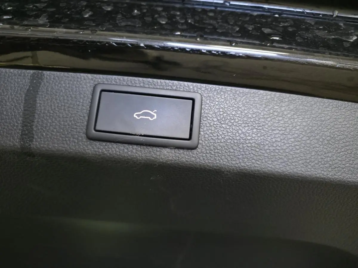 Bouton noir d'ouverture électrique du hayon sur la garniture intérieure d'un Skoda Karoq noir.