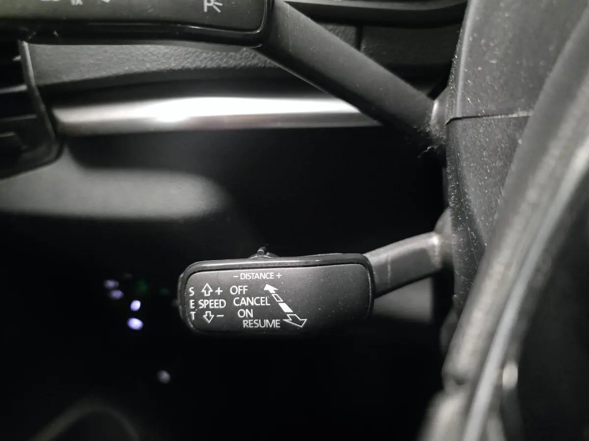 Gros plan sur le commodo de régulateur de vitesse dans l’habitacle noir du Skoda Karoq 2023.