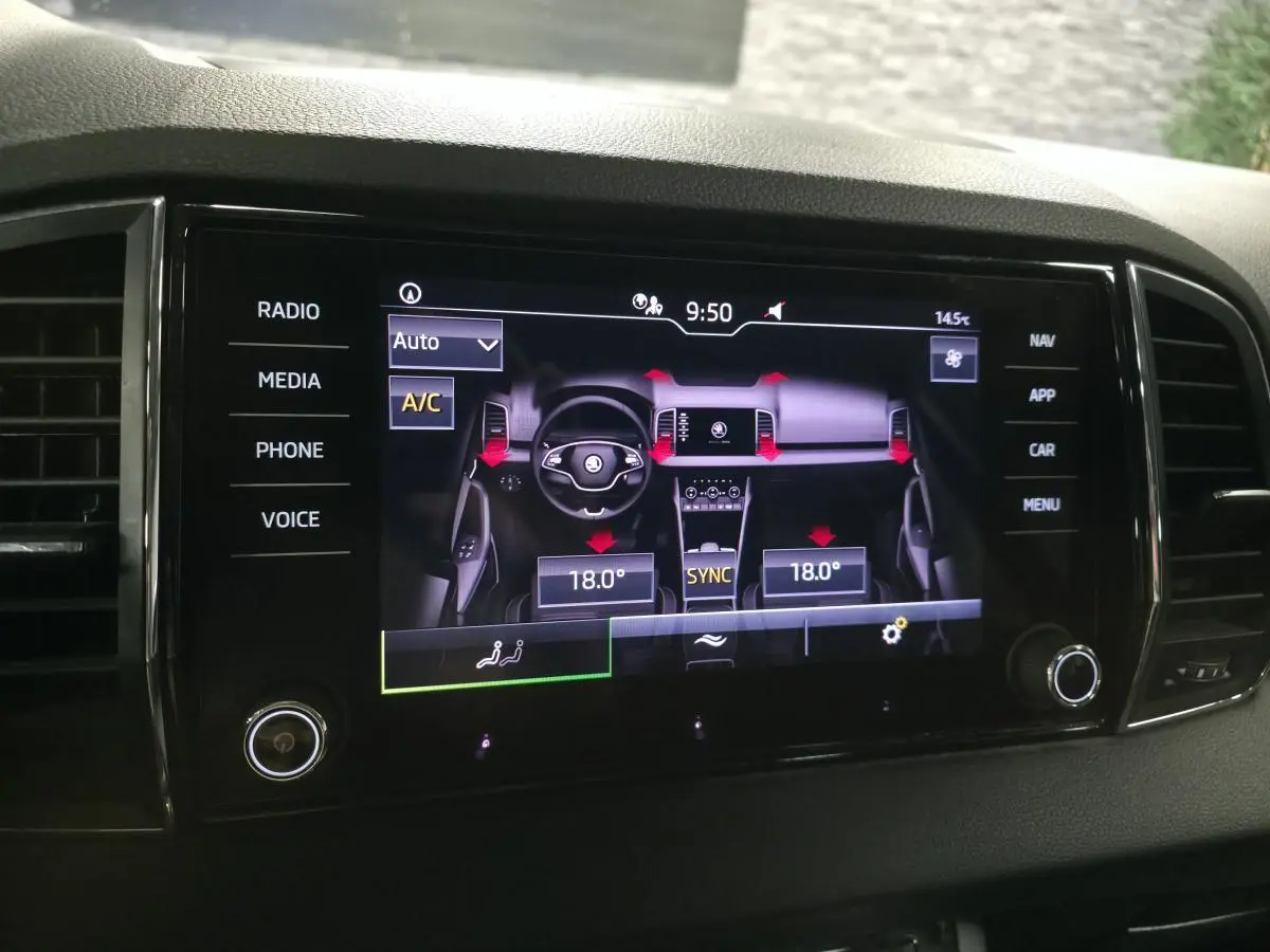 Écran tactile central du Skoda Karoq 2023 affichant la climatisation automatique à 18°C avec commandes digitales.