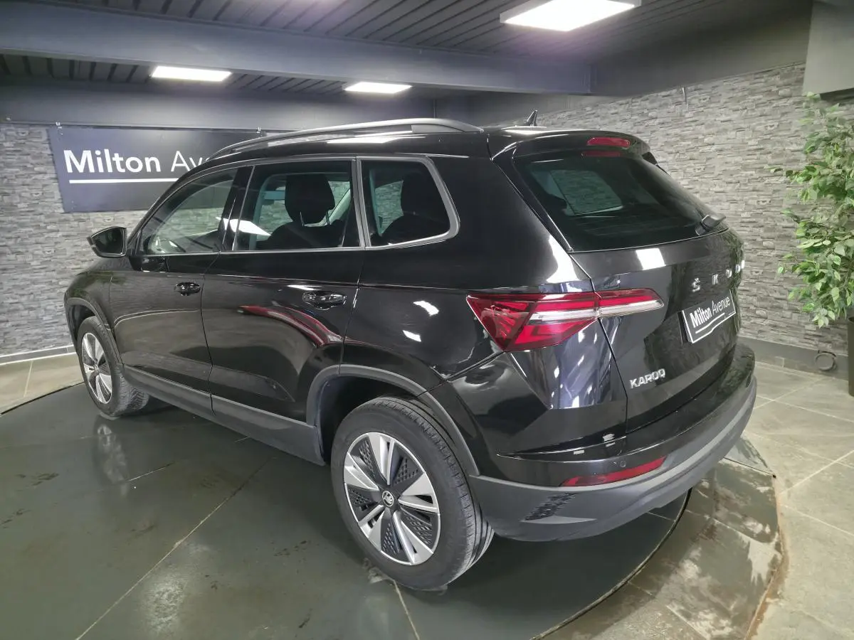 Vue 3/4 arrière droite d'un Skoda Karoq noir 2023 avec jantes alliage et feux arrière LED dans un showroom.
