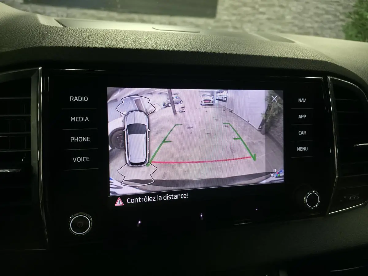 Écran central du Skoda Karoq noir montrant la caméra de recul avec guidage de trajectoire en intérieur de garage.