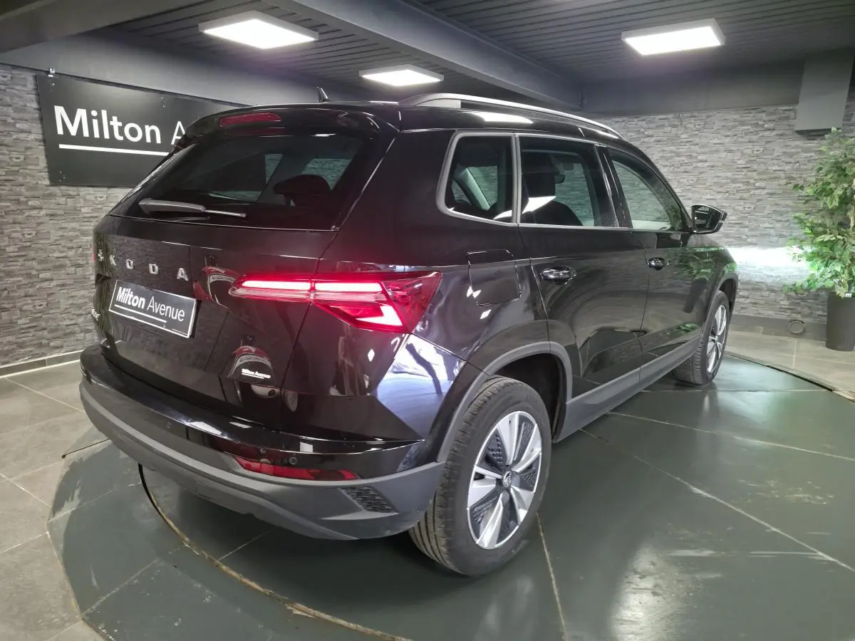 Vue 3/4 arrière droite d'un Skoda Karoq noir 2023 avec feux arrière LED allumés et jantes alliage 17 pouces.