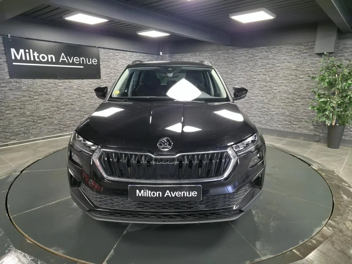 Vue avant d'un Skoda Karoq noir 2023 avec calandre chromée et feux LED dans un showroom.