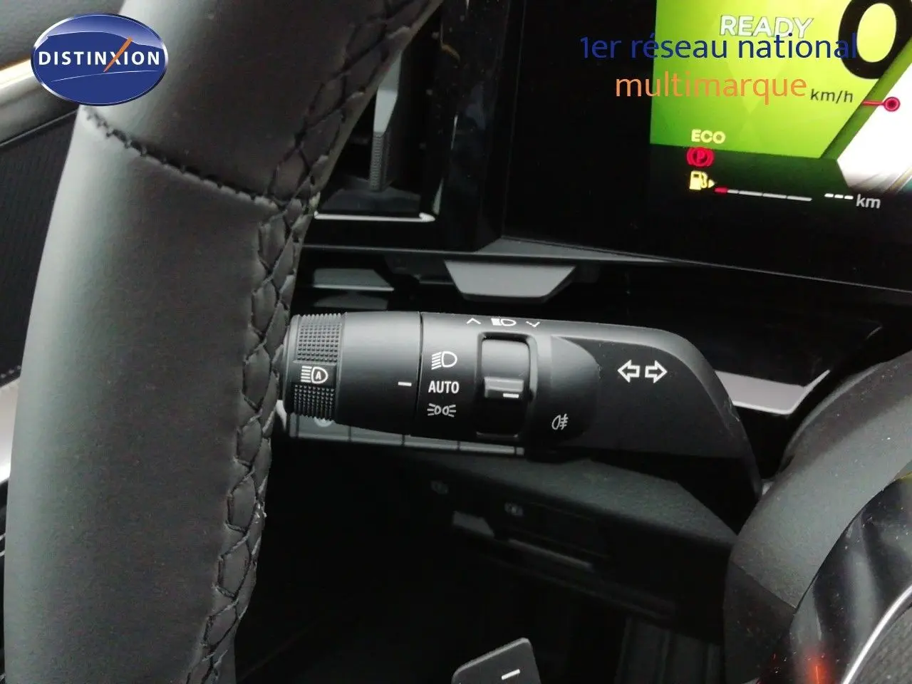 Gros plan sur la manette de clignotants et feux du Renault Austral noir étoile métal, avec tableau de bord digital en arrière-plan.