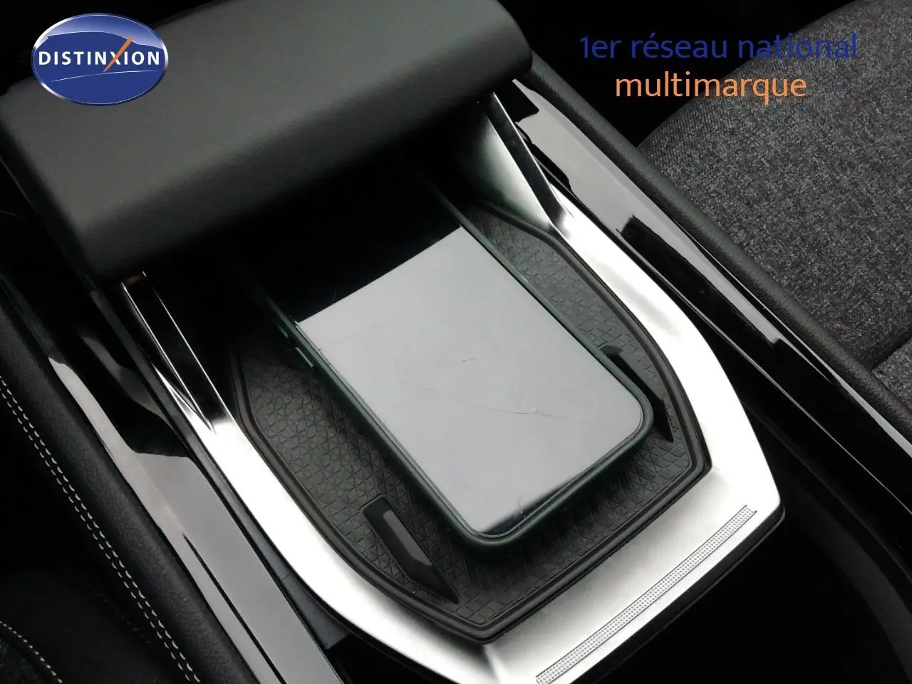 Gros plan sur la console centrale noire du Renault Austral E-Tech avec un smartphone posé sur le chargeur sans fil.