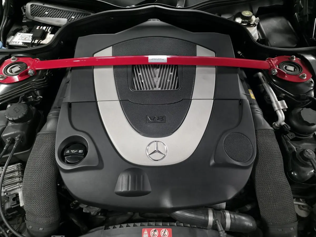 Gros plan sur le moteur V8 Mercedes SL 500 2008 avec barre anti-rapprochement rouge et cache moteur noir et argent.
