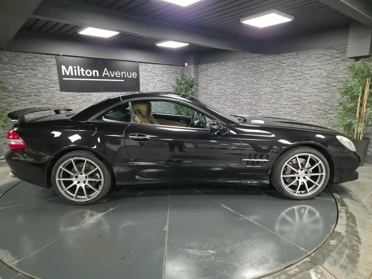 Profil côté gauche d'une Mercedes SL 500 noire de 2008 avec jantes alliage 19 pouces et toit rigide escamotable.