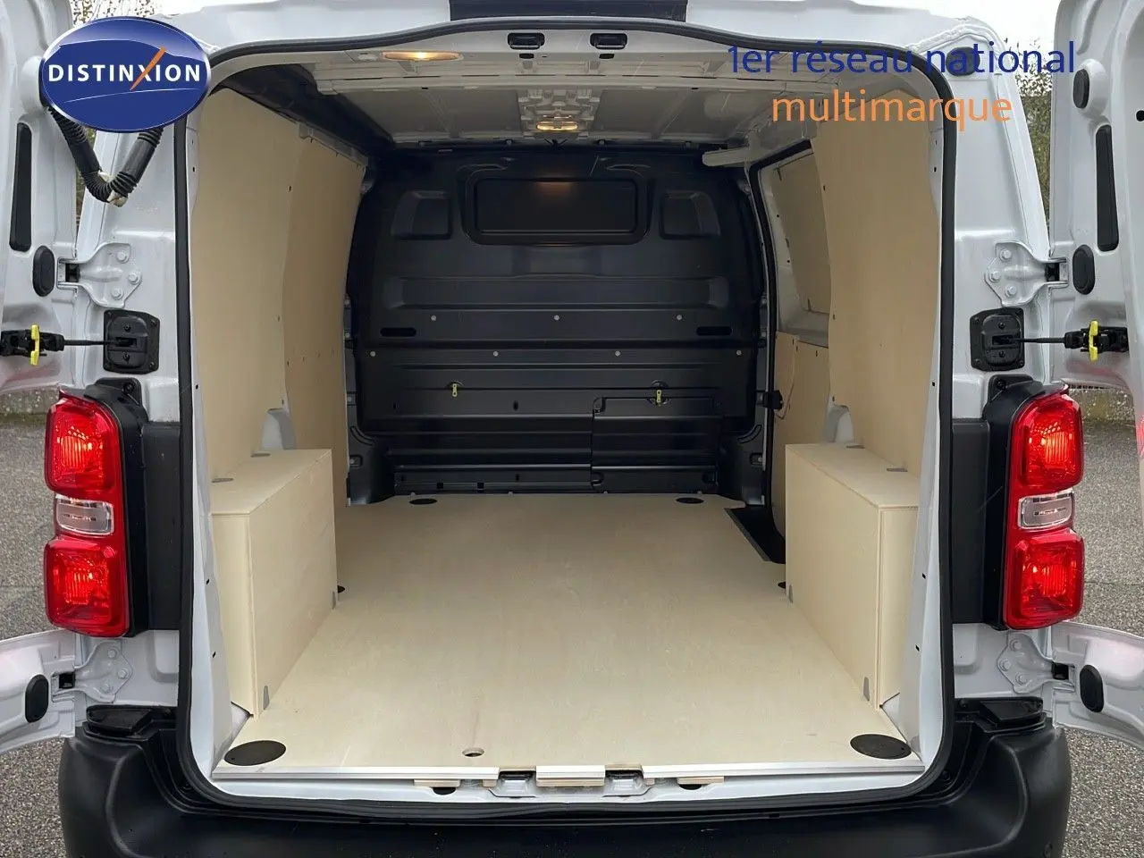 Vue arrière du Peugeot Expert Fourgon blanc 2025 montrant l'espace de chargement aménagé avec revêtement bois clair.