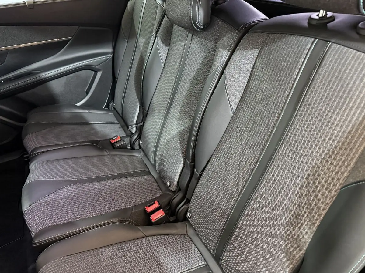 Vue latérale des sièges arrière gris tissu et cuir du Peugeot 5008, version Allure Pack 2021, avec ceintures rouges visibles.