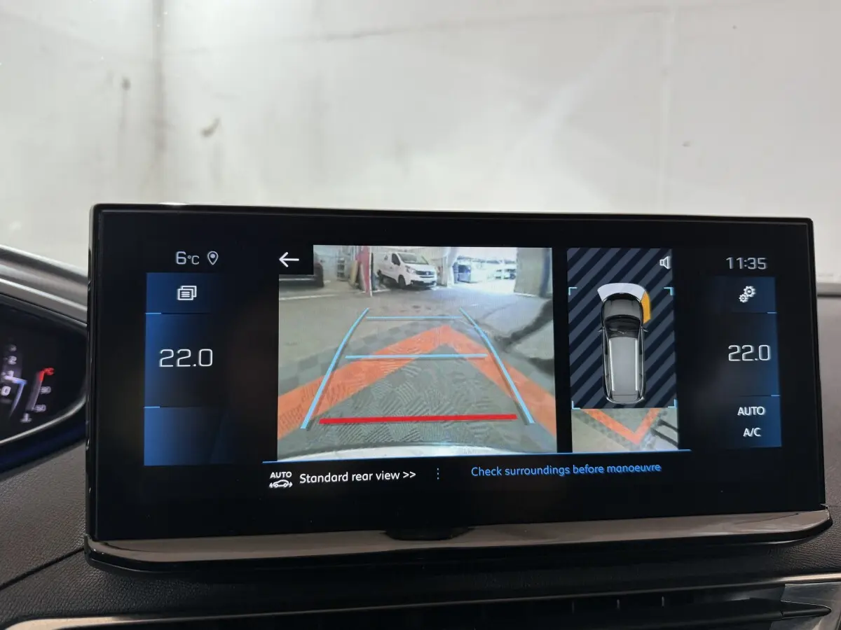 Écran tactile intérieur du Peugeot 5008 gris clair montrant la caméra de recul et l’aide au stationnement arrière.