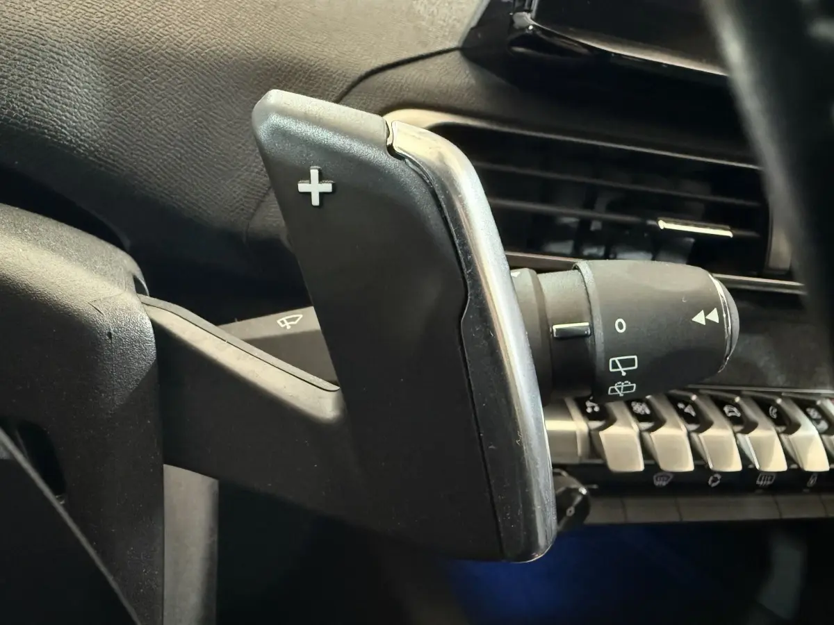 Gros plan sur la palette de changement de vitesse droite dans l’habitacle noir du Peugeot 5008 gris clair 2021.