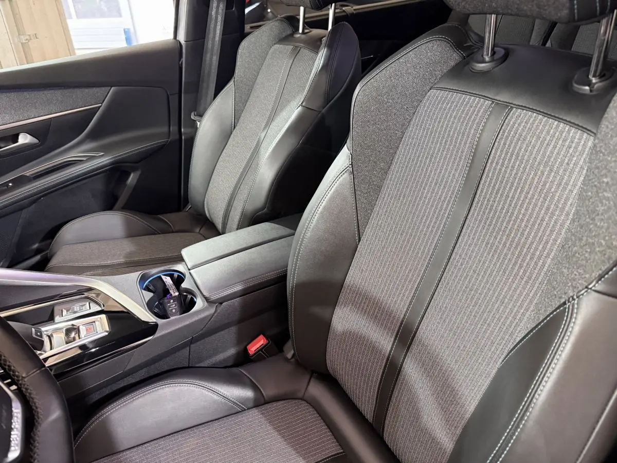 Vue intérieure côté avant droit du Peugeot 5008 2021, sièges tissu et cuir gris avec console centrale et commandes modernes.