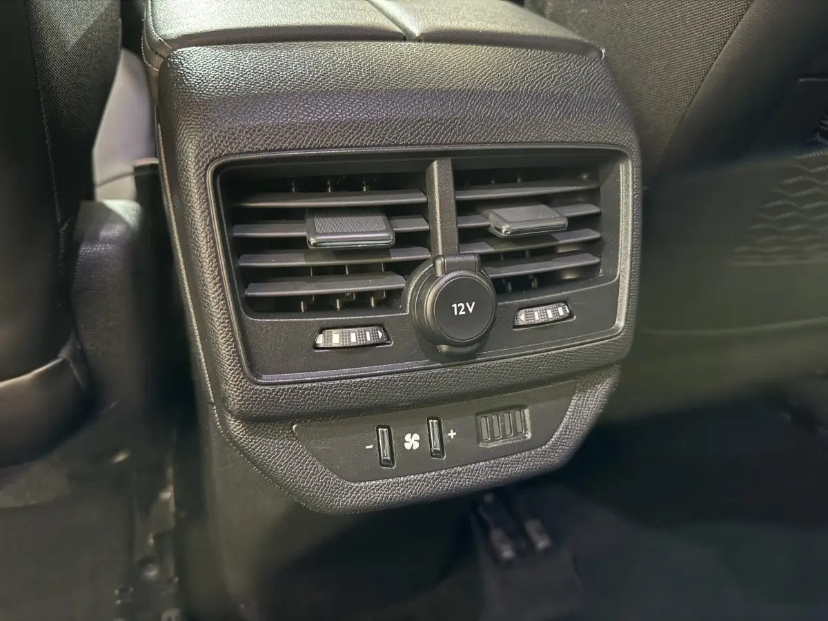 Détail de la console arrière noire avec prise 12V et commandes de ventilation du Peugeot 5008 gris clair, vue intérieure rapprochée.