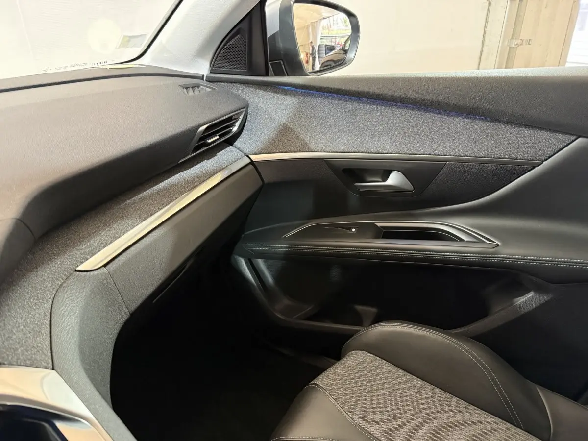 Vue intérieure côté passager du Peugeot 5008 2021, montrant la portière noire et le tableau de bord gris avec inserts métalliques.