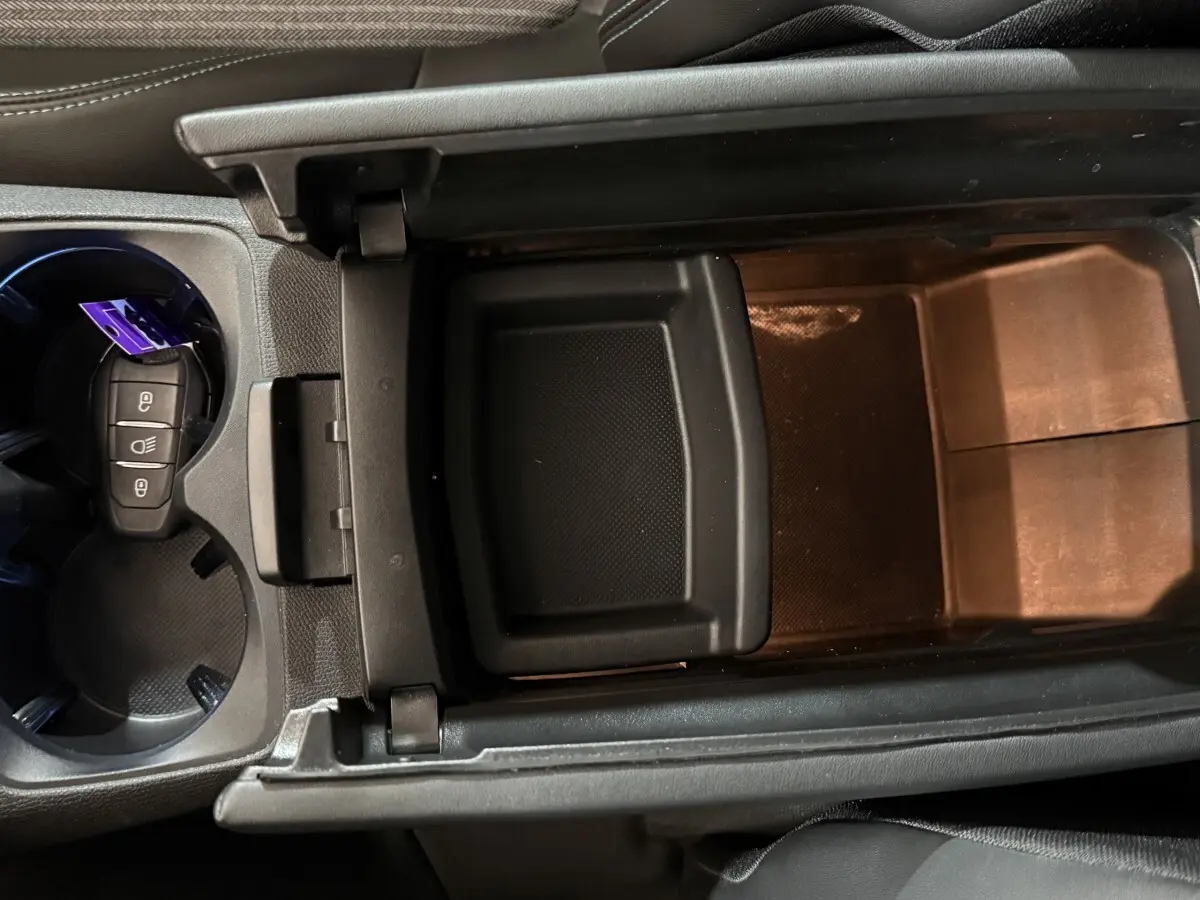 Vue plongeante sur le rangement central noir et porte-clés dans les porte-gobelets du Peugeot 5008 gris clair 2021.