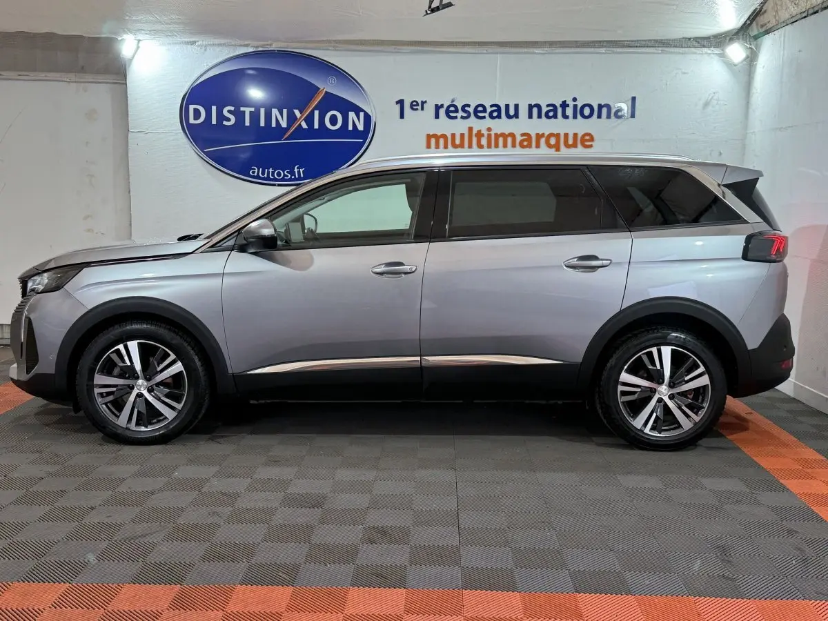 Vue de profil côté gauche d'un Peugeot 5008 gris clair, SUV avec jantes alliage et vitres teintées.