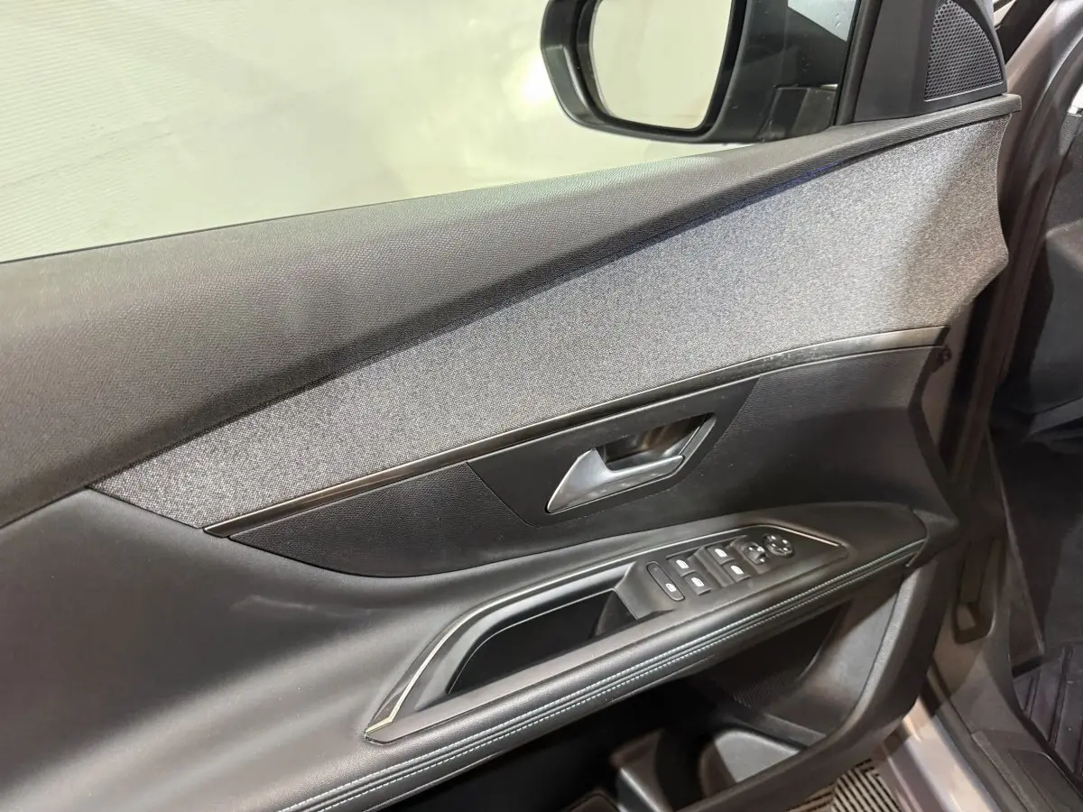 Vue intérieure côté gauche de la porte avant du Peugeot 5008 gris clair, avec commandes de vitres et rétroviseur.