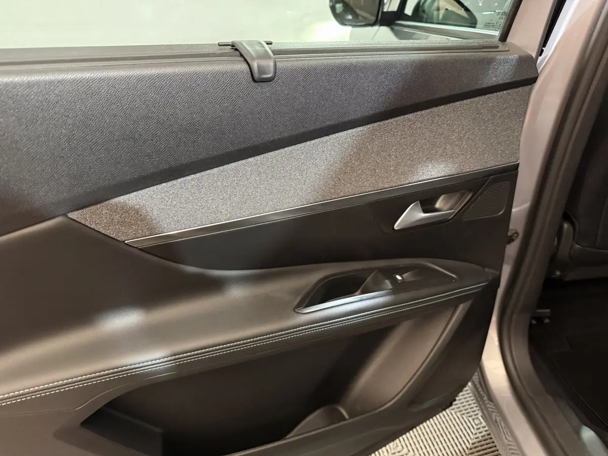 Vue intérieure du panneau de porte arrière droite gris clair du Peugeot 5008 avec garniture noire et bouton de lève-vitre.