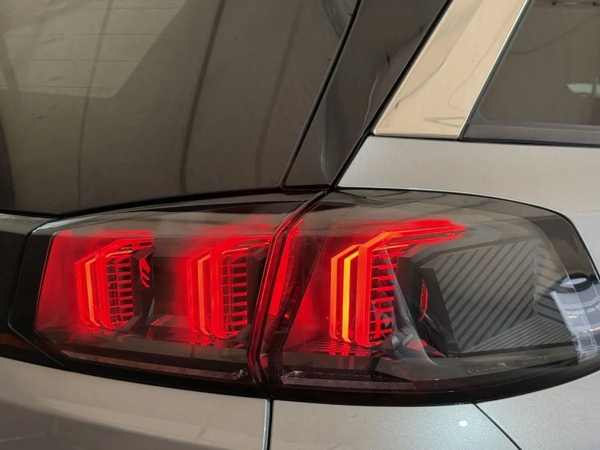Gros plan sur le feu arrière droit rouge du Peugeot 5008 gris clair, soulignant le design en trois griffes LED.
