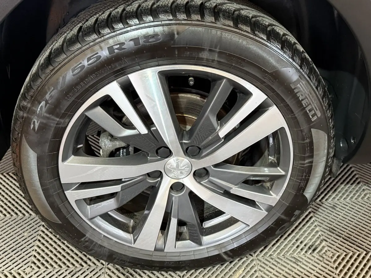 Gros plan sur la jante alliage gris et noir avec logo Peugeot, montée sur pneu Pirelli 225/55 R18 du 5008 gris clair.