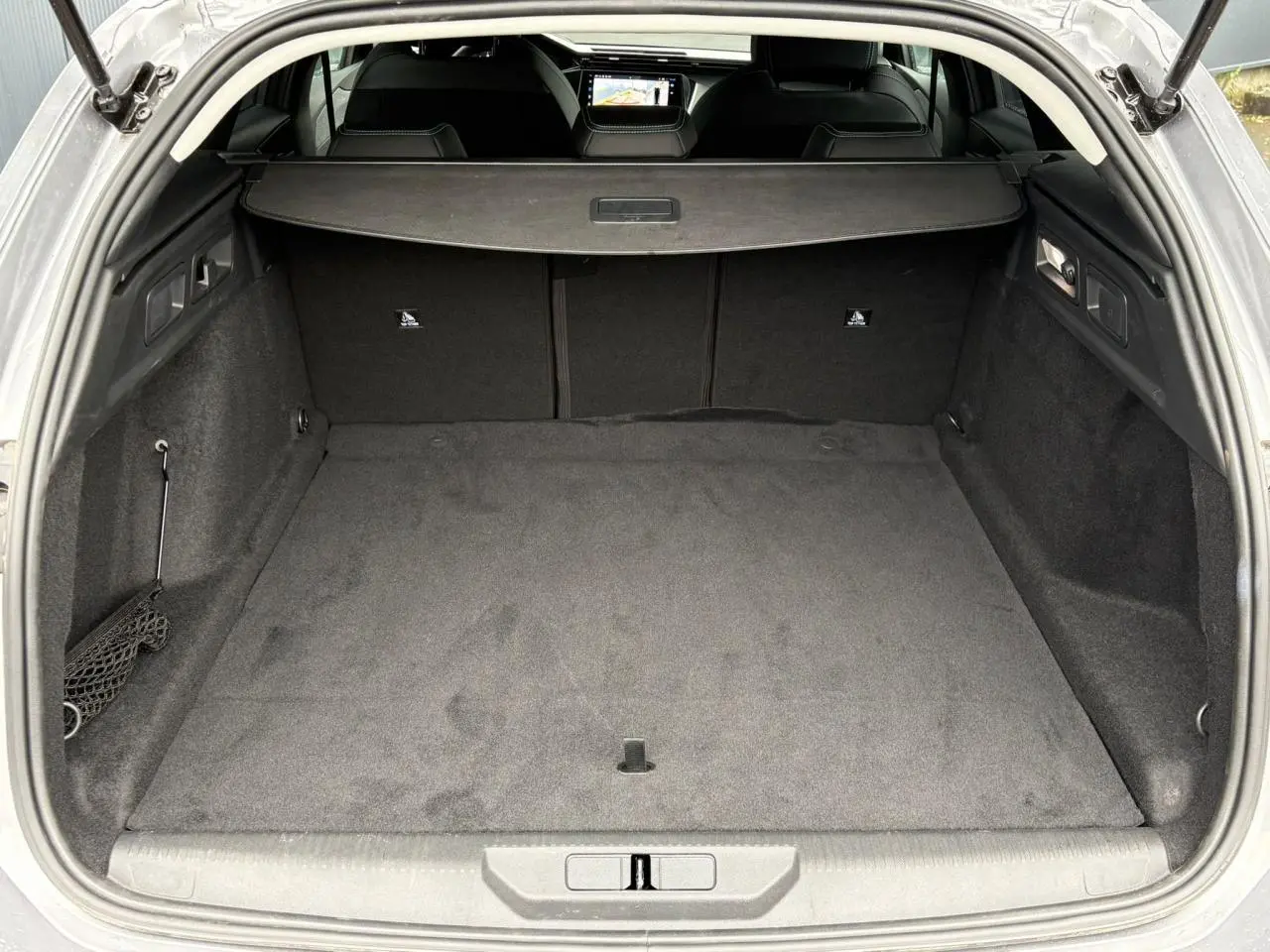 Coffre ouvert vu de l'arrière d'une Peugeot 308 SW gris Artense, avec cache-bagages et intérieur noir.