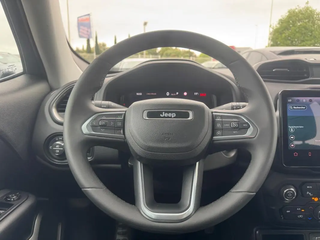 Vue centrée sur le volant du Jeep Renegade 2024, intérieur noir avec écran tactile et commandes au volant visibles.