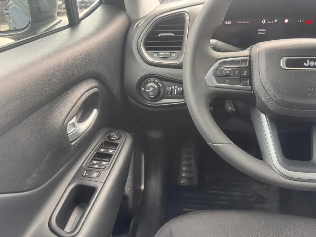 Vue intérieure côté conducteur du Jeep Renegade 2024, volant, commandes des vitres et tableau de bord partiel visibles.