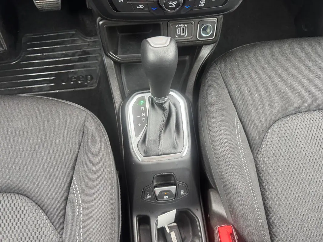 Vue rapprochée de la console centrale avec levier de vitesse automatique et sièges noirs du Jeep Renegade 2024.