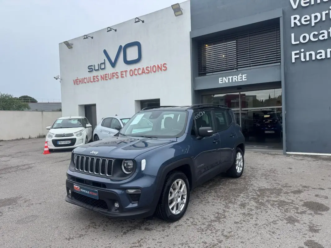Jeep Renegade bleu en 3/4 avant droit, avec jantes alliage 17 pouces, stationné devant un concessionnaire.
