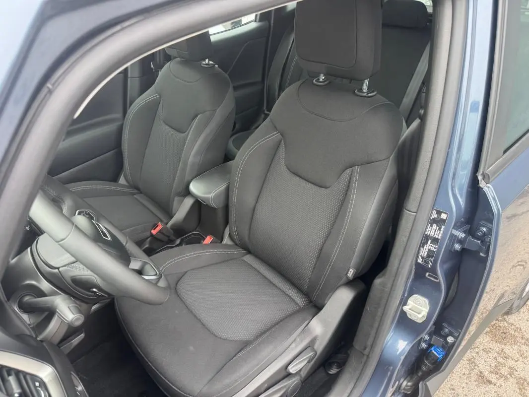 Vue intérieure côté conducteur du Jeep Renegade 2024 bleu, avec sièges tissu noirs et accoudoir central visible.