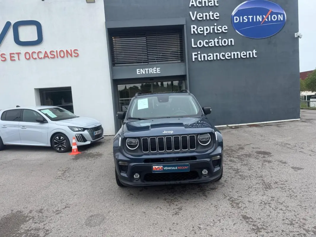 Jeep Renegade bleu vue de face, avec calandre à sept fentes et phares ronds, stationné devant un bâtiment commercial.