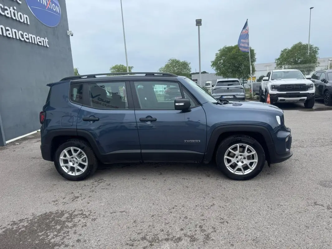 Jeep Renegade bleu en profil droit, avec barres de toit et jantes alliage 17 pouces visibles sur parking.