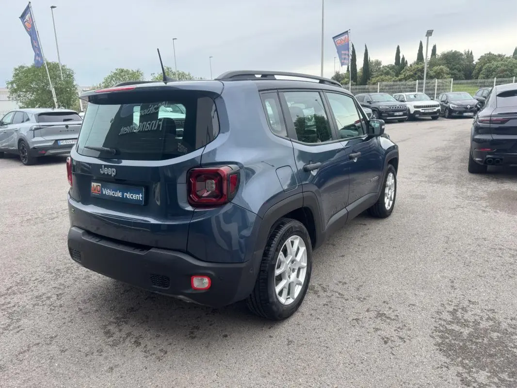 Jeep Renegade bleu vue 3/4 arrière droit, avec barres de toit et jantes alliage 17 pouces visibles.