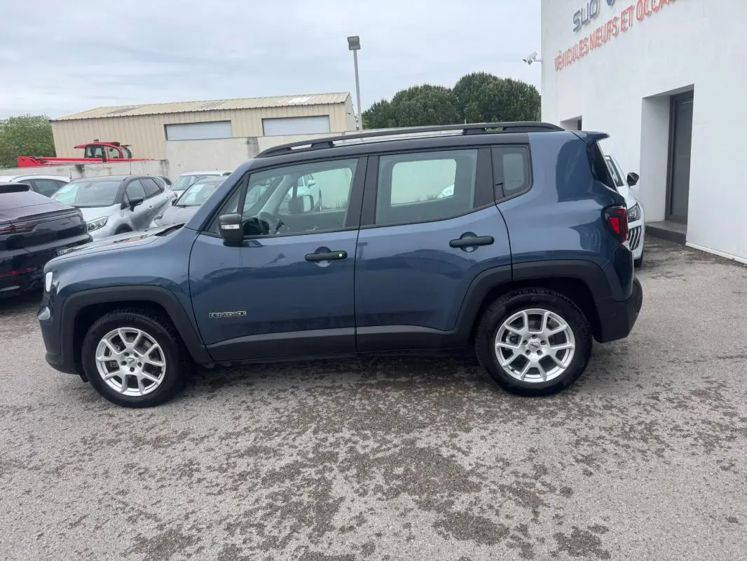 Vue de profil côté gauche d'un Jeep Renegade bleu 2024 avec barres de toit et jantes alliage 17 pouces.