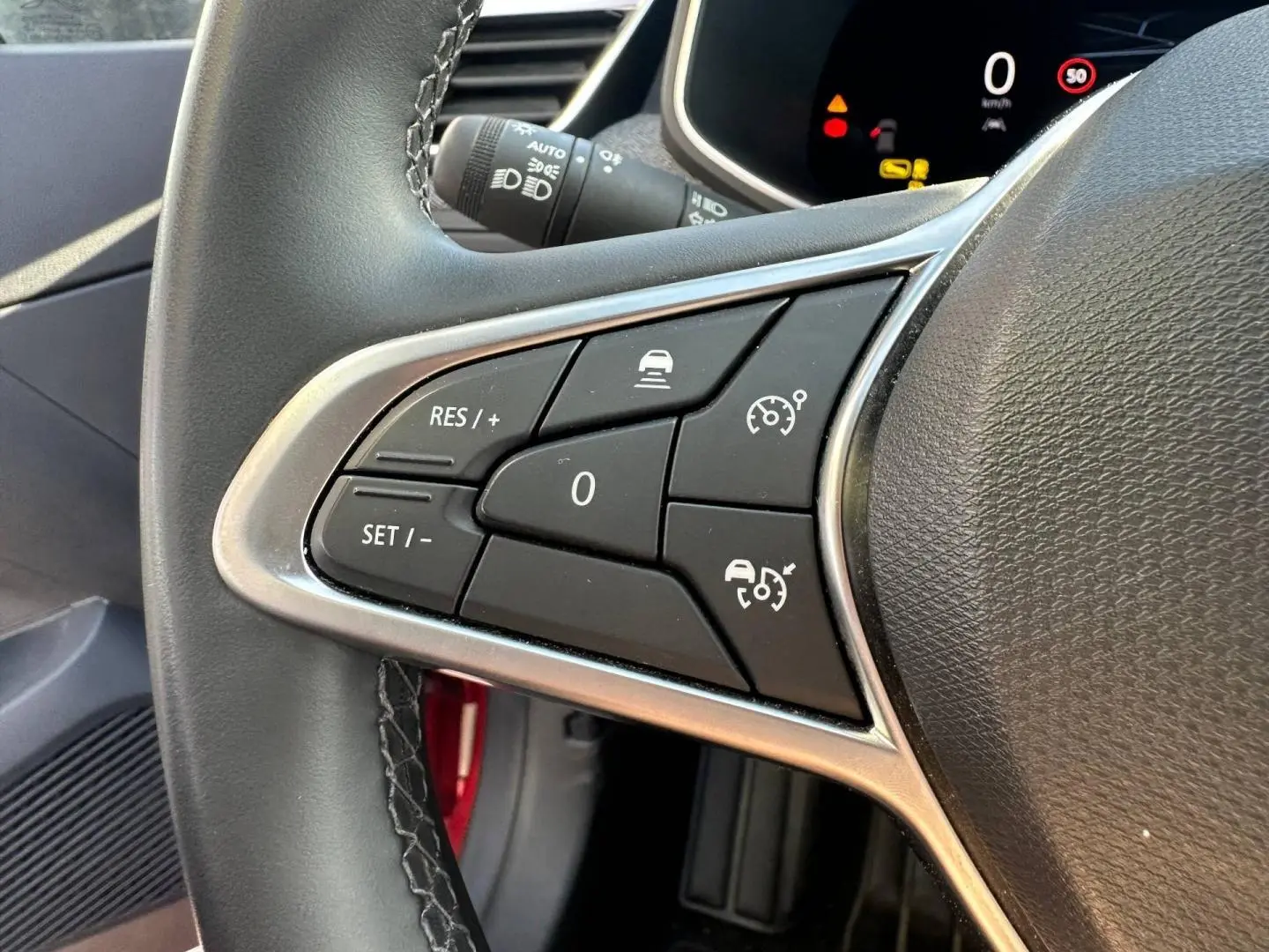 Gros plan sur les commandes multifonctions du volant côté gauche de la Renault Clio Rouge Flamme 2025.