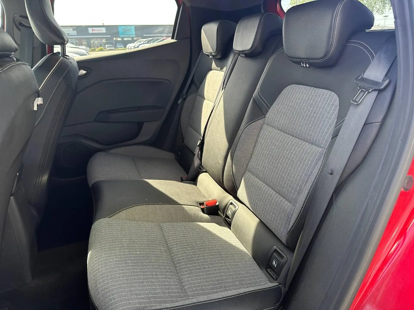 Vue côté droit de la banquette arrière grise et noire de la Renault Clio Rouge Flamme avec ceinture de sécurité visible.