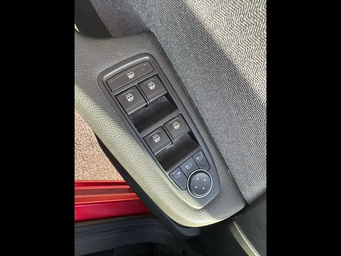Détail des commandes des vitres électriques sur la porte avant gauche d'une Renault Clio Rouge Flamme 2025.