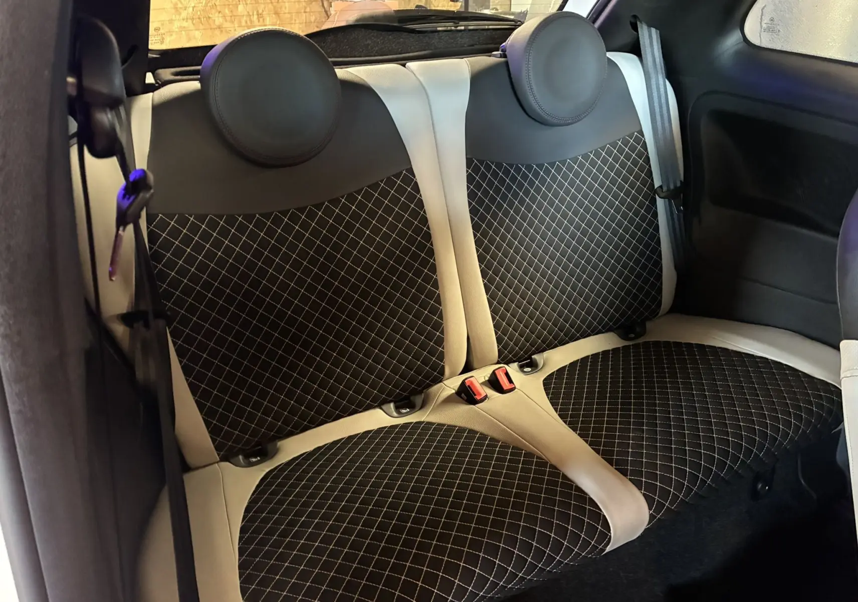 Vue intérieure sur les sièges arrière en tissu noir à motifs blancs de la Fiat 500 blanche, version DolceVita 2021.