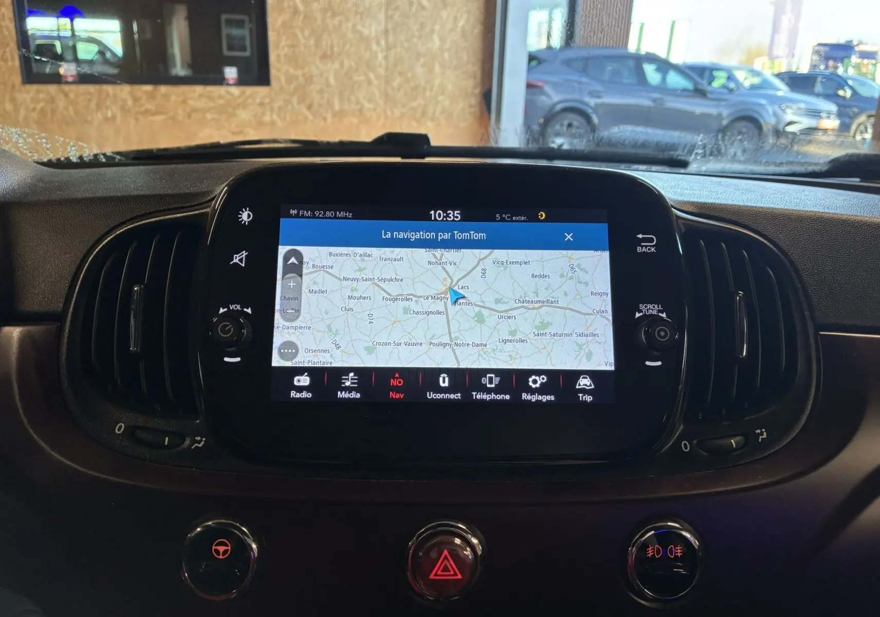 Vue intérieure centrée sur l'écran tactile de navigation du tableau de bord d'une Fiat 500 blanche de 2021.