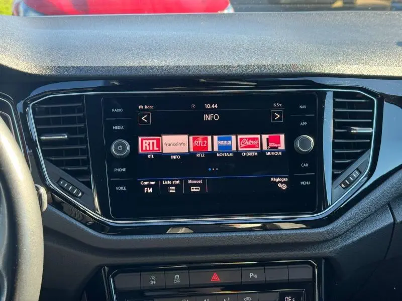 Vue rapprochée de l'écran tactile central noir du Volkswagen T-Roc 2019 affichant les stations radio FM.
