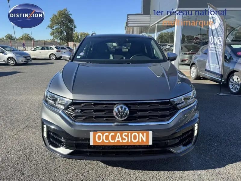 Vue avant d'un Volkswagen T-Roc gris métallisé avec calandre noire et plaque "OCCASION" en concession.