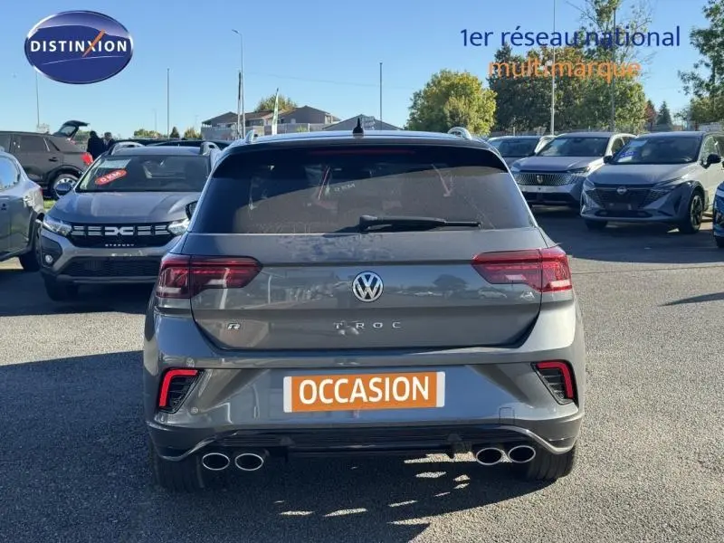 Vue arrière d'un Volkswagen T-Roc gris avec double sortie d'échappement et feux arrière LED en stationnement.