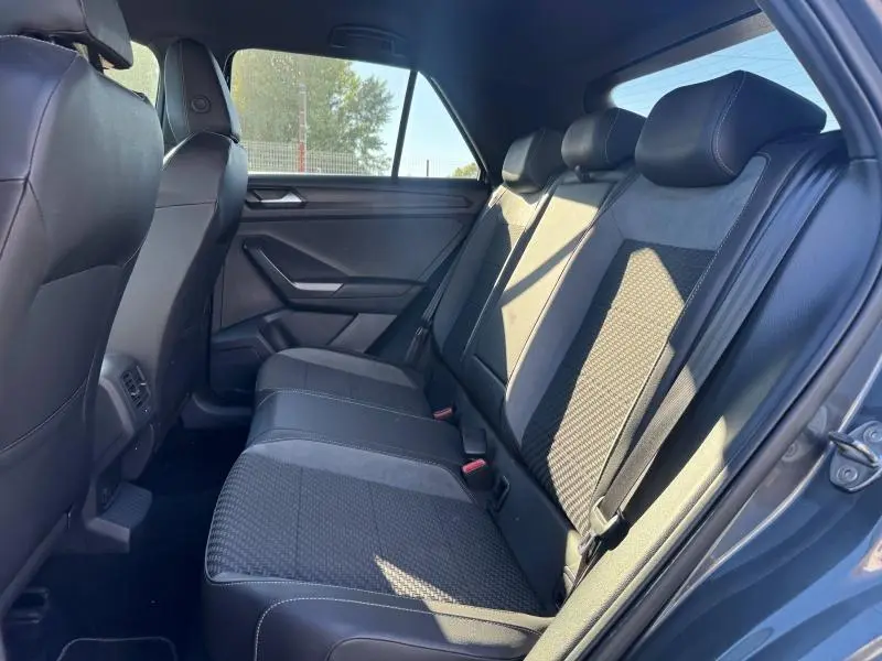 Vue latérale droite de l'intérieur arrière du Volkswagen T-Roc 2019, sièges tissu/simili-cuir noir avec ceintures visibles.