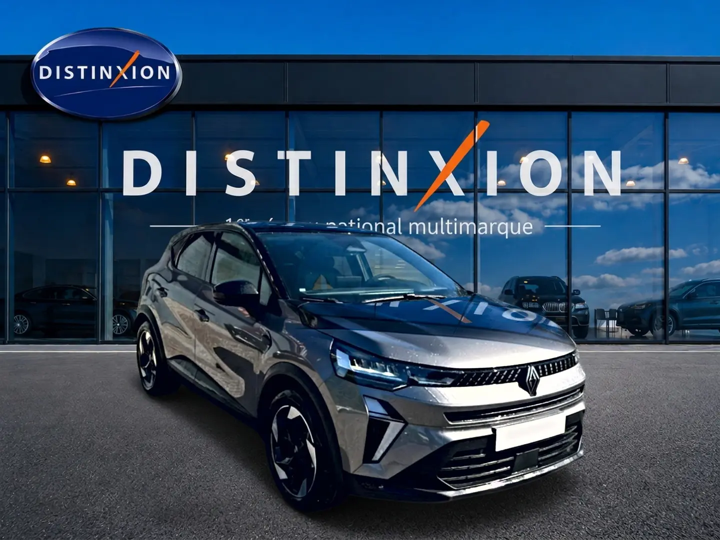Renault Captur gris cassiopée en 3/4 avant droit, avec calandre moderne et jantes alu noires devant showroom Distinxion.